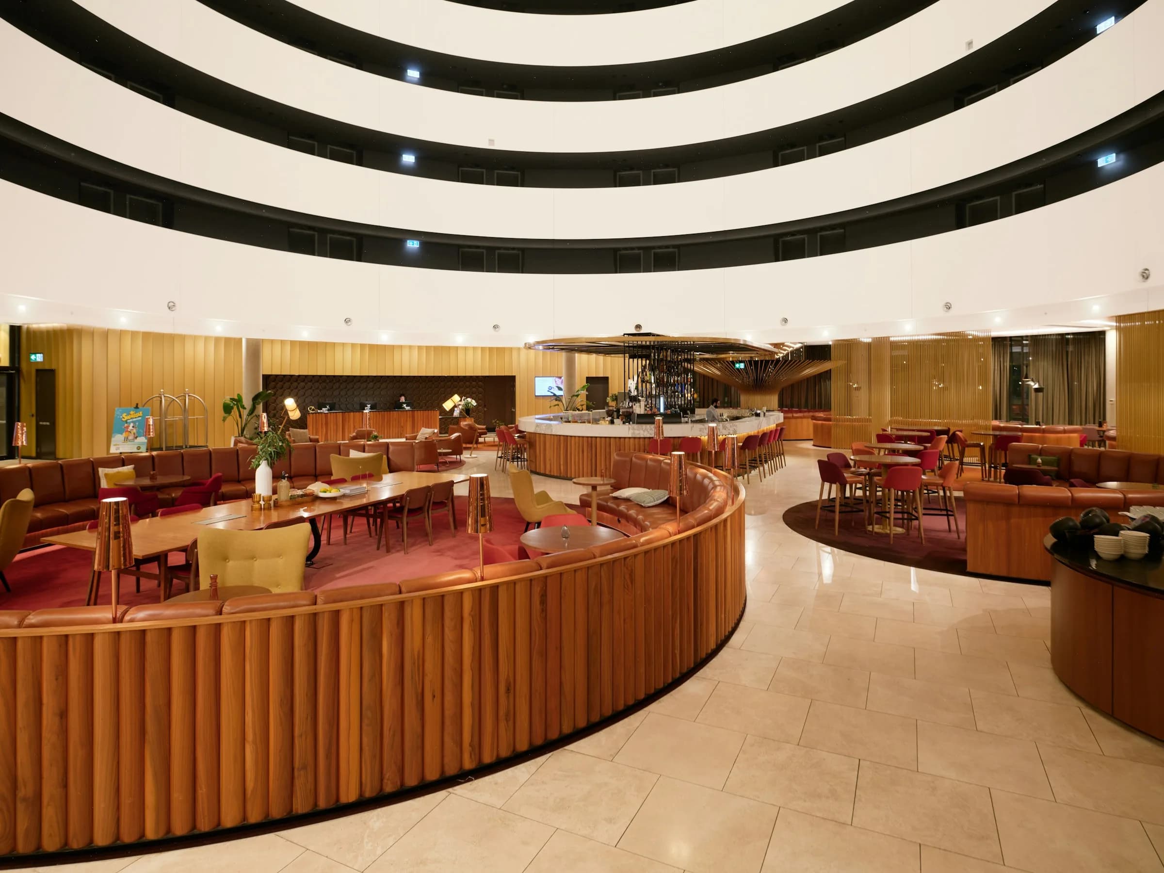 Ahşap kaplamalı otel lobisi, deri oturma grupları ve bar